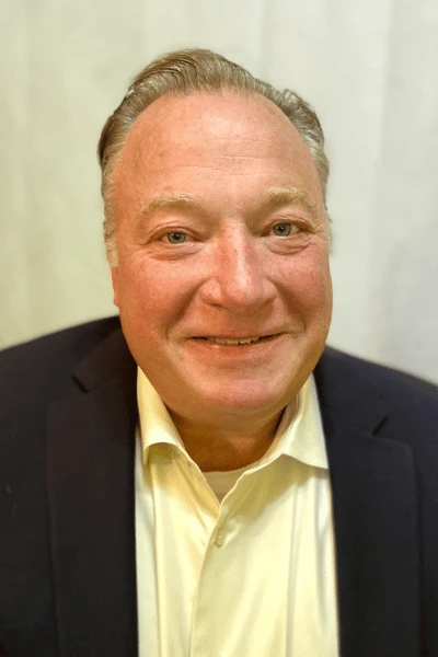 Headshot of RJM Change Management founder Russell Morse smiling into the camera while wearing a collared shirt and suit jacket