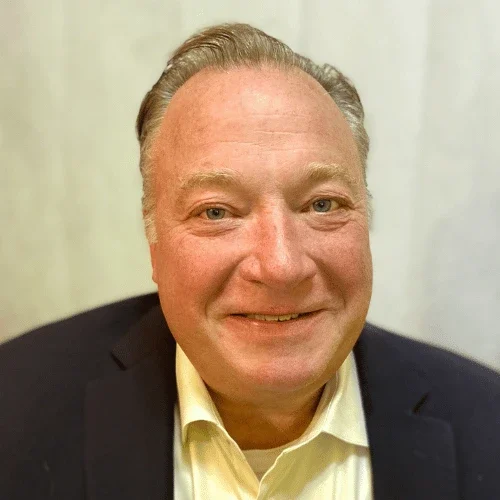 Headshot of RJM Change Management founder Russell Morse smiling into the camera while wearing a collared shirt and suit jacket